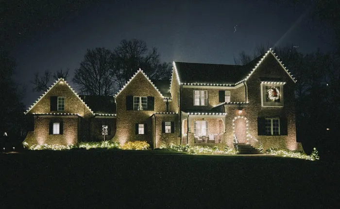 Holiday lighting along a home's porch, columns, and landscaping