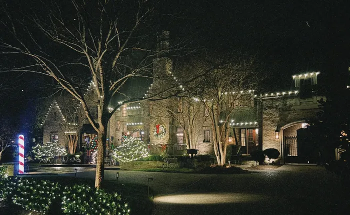 A tree wrapped in warm white Christmas lights in a Williamson County yard