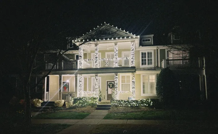 Holiday lighting along a home's porch, columns, and landscaping