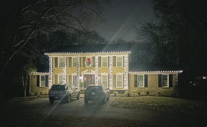 A tree wrapped in warm white Christmas lights in a Williamson County yard