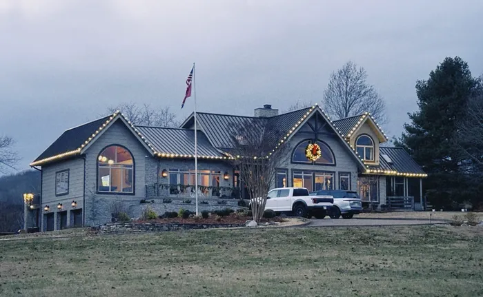 Holiday lighting along a home's porch, columns, and landscaping