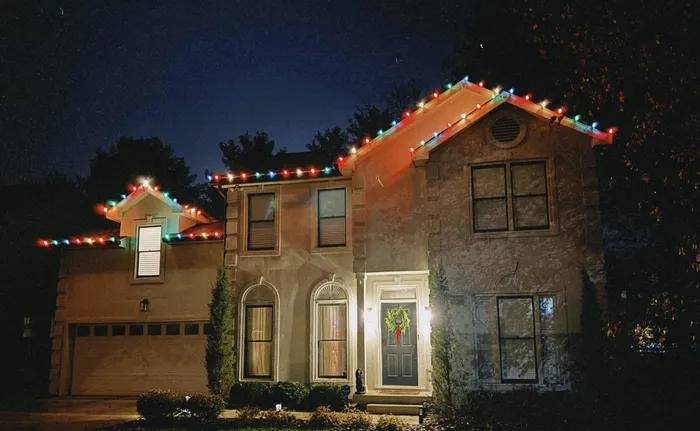 Holiday lighting along a home's porch, columns, and landscaping