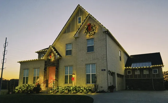 Custom Christmas lights installed along the roofline and landscaping of a Williamson County home