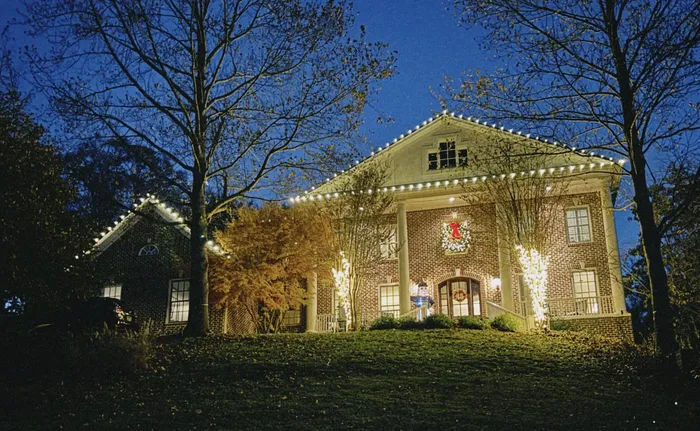 Holiday lighting along a home's porch, columns, and landscaping